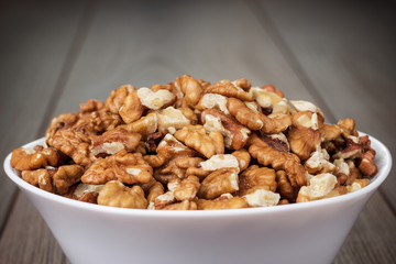 walnuts in the white bowl on wooden table