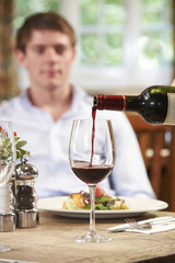 Waitress Pouring Customer Glass Of Red Wine