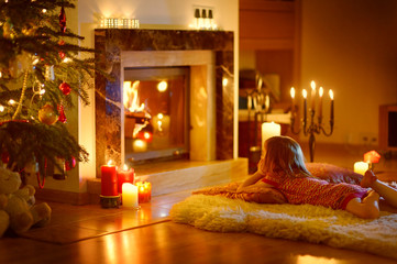 Happy little girl by a fireplace on Christmas