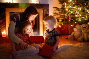 Mother and her daughters opening a Christmas gift