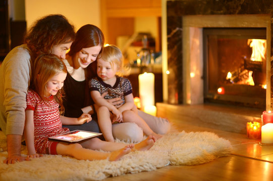 Happy young family using a tablet pc at home by a fireplace