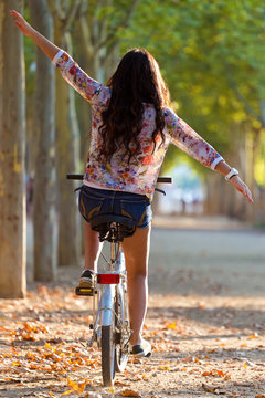 Pretty young girl riding bike in a forest.
