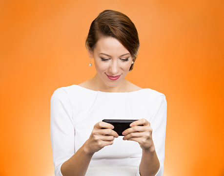 Woman texting on smart phone on orange background 