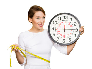 Happy Female holding clock, measuring her waist with tape