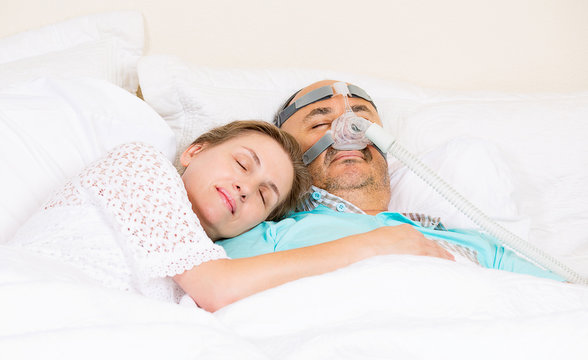 Man with sleeping apnea and CPAP machine asleep in bed