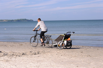 Fahrradfahrer mit Kinderanhänger am Strand