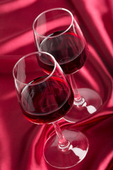 Two wine glasses with red wine on the red silk