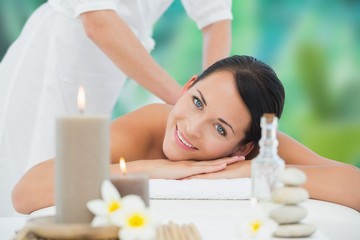 Obraz na płótnie Canvas Beautiful brunette enjoying a back massage smiling at camera
