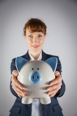 Fototapeta na wymiar Smiling businesswoman showing piggy bank
