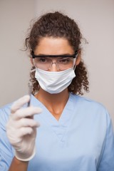 Dentist in surgical mask and scrubs holding tool
