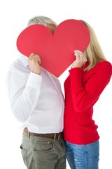 Couple embracing and holding heart over faces