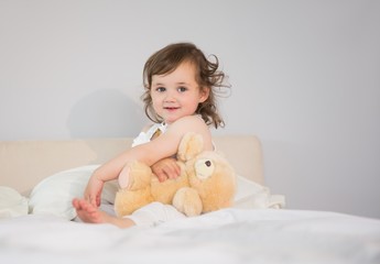 Portrait of cute little girl sitting on bed