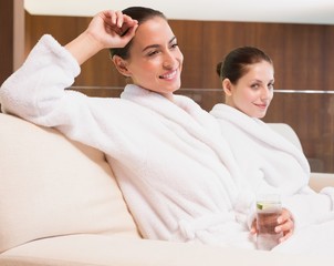 Obraz na płótnie Canvas Smiling women in bathrobes drinking water
