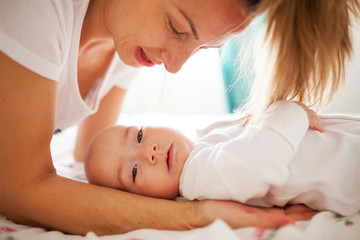 Obraz na płótnie Canvas Mother holding baby on bed