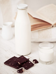 Still life interior details, glass of milk, chocolate and a book