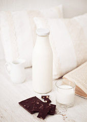 Still life interior details, glass of milk, chocolate and a book