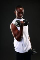 Fototapeta na wymiar Portrait of african man working out with dumbbells