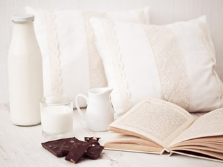 Still life interior details, glass of milk, chocolate and a book