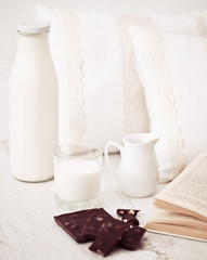 Still life interior details, glass of milk, chocolate and a book