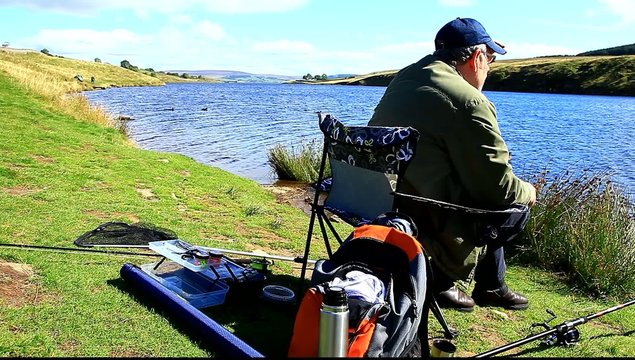 man fishing at grassholme reservoir uk