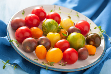 Naklejka na ściany i meble colorful tomatoes in plate on blue background