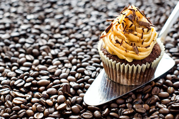 Muffin with caramel cream on coffee beans copyspace background