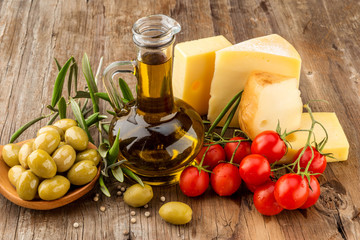 Olives oil,green olive, cheese and cherry tomato on wood