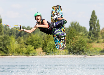 Jugendlicher Wakeboarder zeigt DAUMEN HOCH im Flug