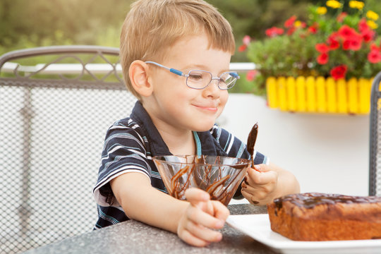 Kleiner Junge beim Schokoladenkuchen verzieren