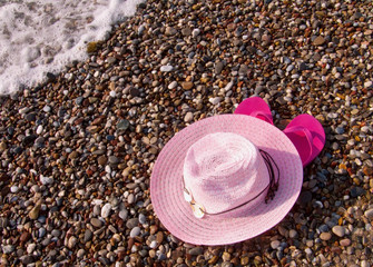 Sun hat and flip flop on the beach. 