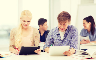 two smiling students with tablet pc at school