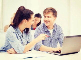 two smiling students with laptop computer