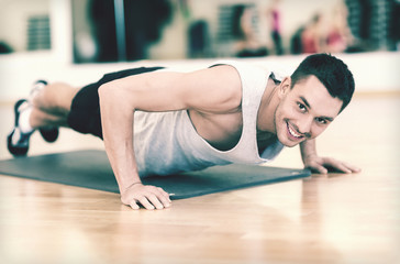 Obraz na płótnie Canvas smiling man doing push-ups in the gym