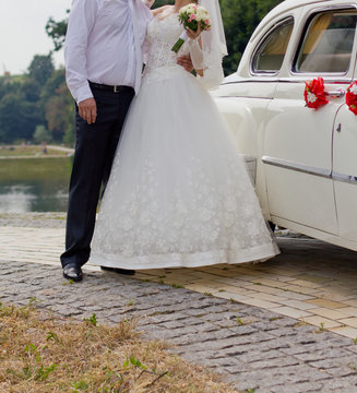 Bride and groom posing by a car
