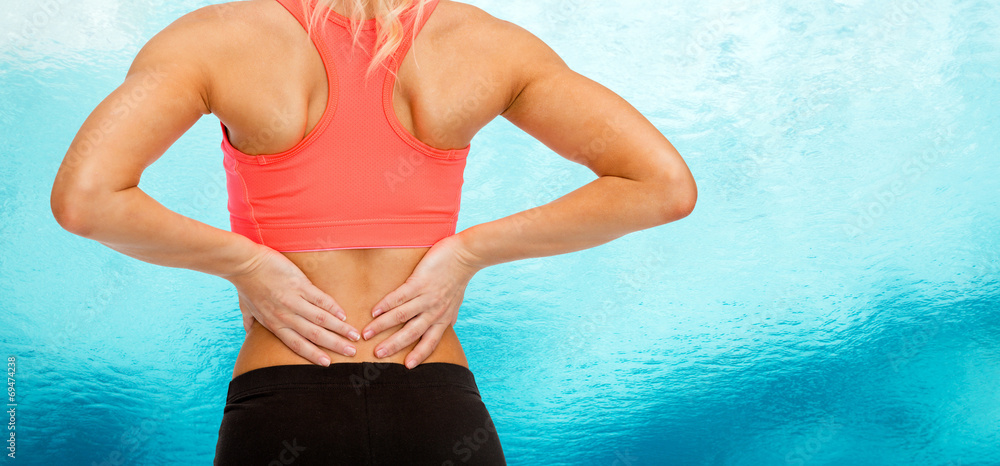 Poster close up of sporty woman touching her back