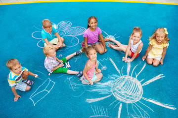 Group of children draw with chalk on playground