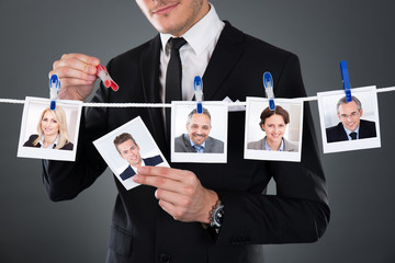 Businessman Selecting Candidate From Clothesline