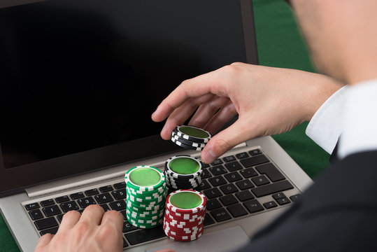 Businessman Using Laptop With Stacked Poker Chips