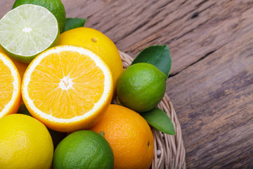 Obraz na płótnie Canvas Mix of fresh citrus fruits in basket on wood