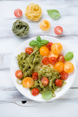 Plate with colored tagliatelle and roasted tomatoes, above view