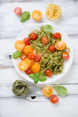 Colored tagliatelle and fried tomatoes with basil, above view