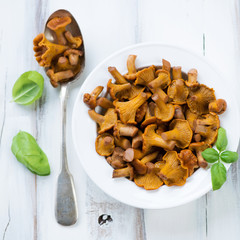 Glass plate with marinated chanterelles and basil, above view