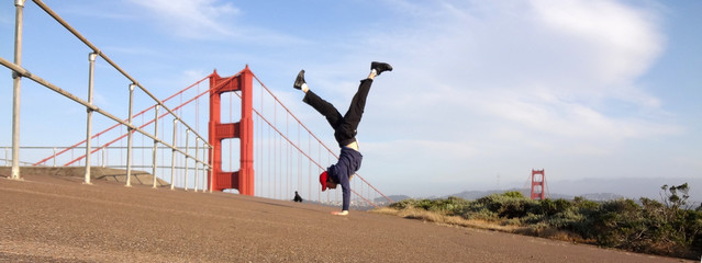 Man wearing hat, hoodie, long pants and shoes Handstands in fron