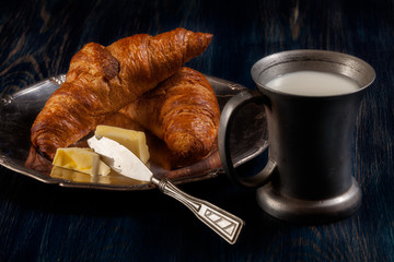 Croissants with butter and a glass of milk