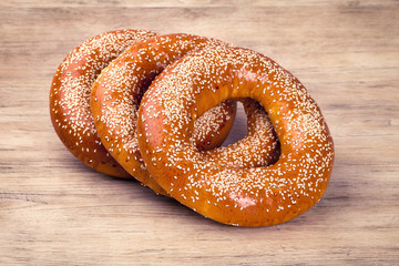Baked bagels sprinkled with sesame seeds on wooden table