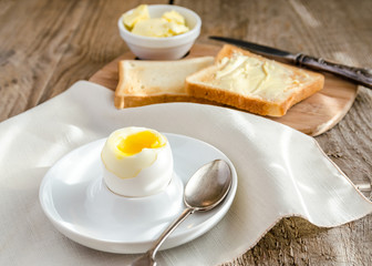 Boiled egg with crispy toasts on the wooden table