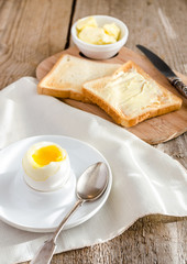 Boiled egg with crispy toasts on the wooden table