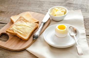 Boiled egg with crispy toasts on the wooden table
