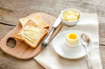 Boiled egg with crispy toasts on the wooden table