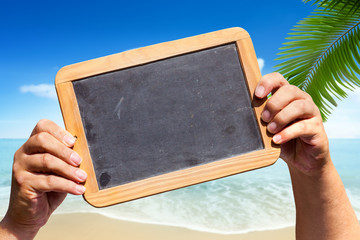 Hände halten leere Tafel am Strand hoch